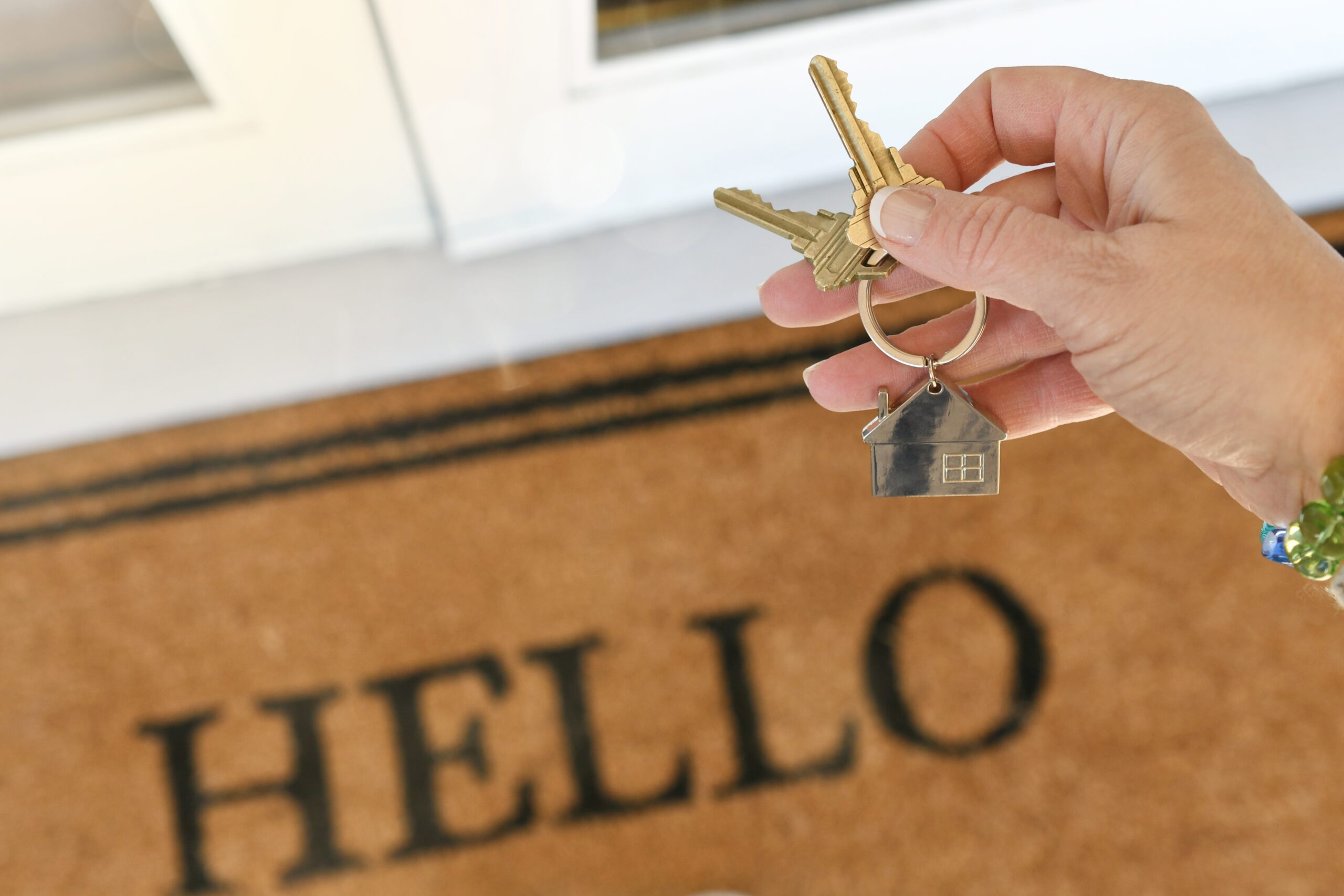 Homeowner holding new house keys over welcome mat by Capstone Custom Homes