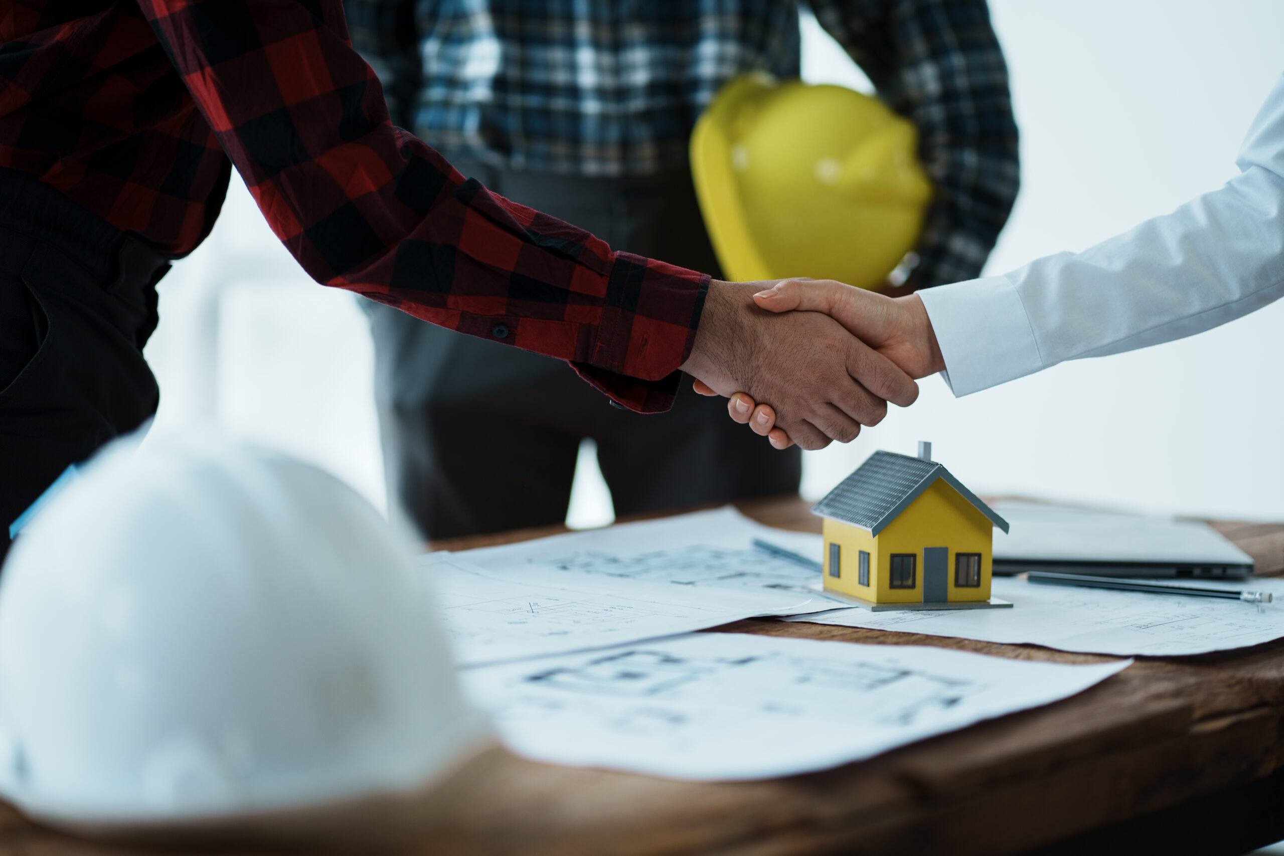 Contractor and client shaking hands over home plans by Capstone Custom Homes